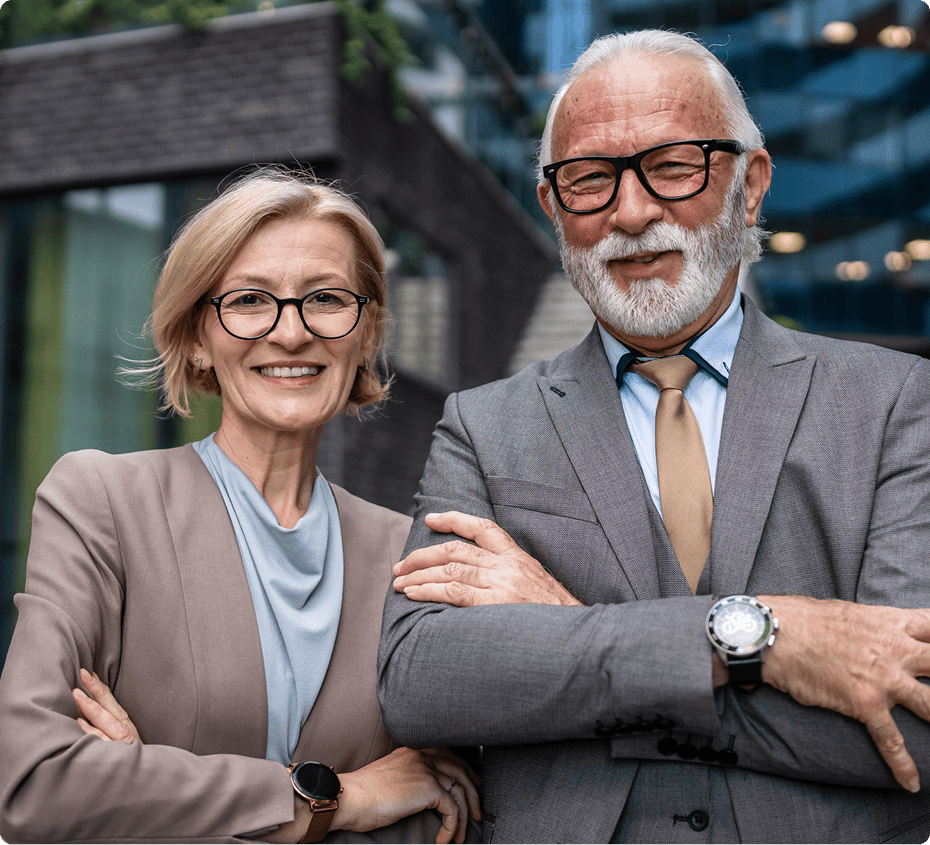 Smiling elderly man and woman in suits.